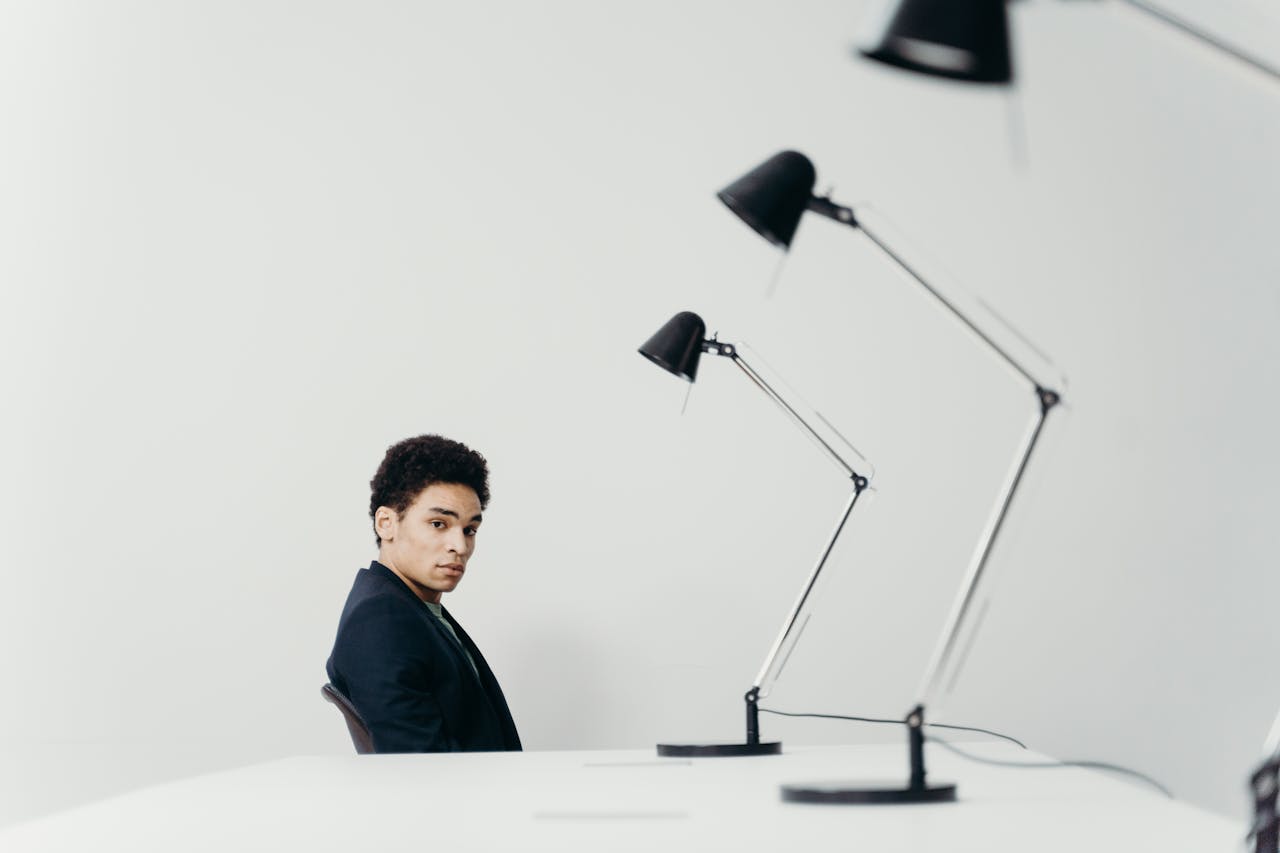 Young man in modern office setting with sleek lamps and minimal design.